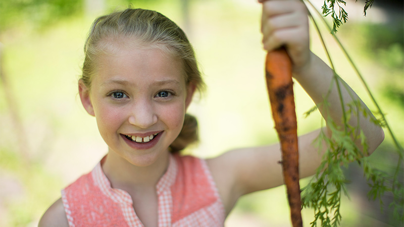 Outdoor image of a young girl with a carrot